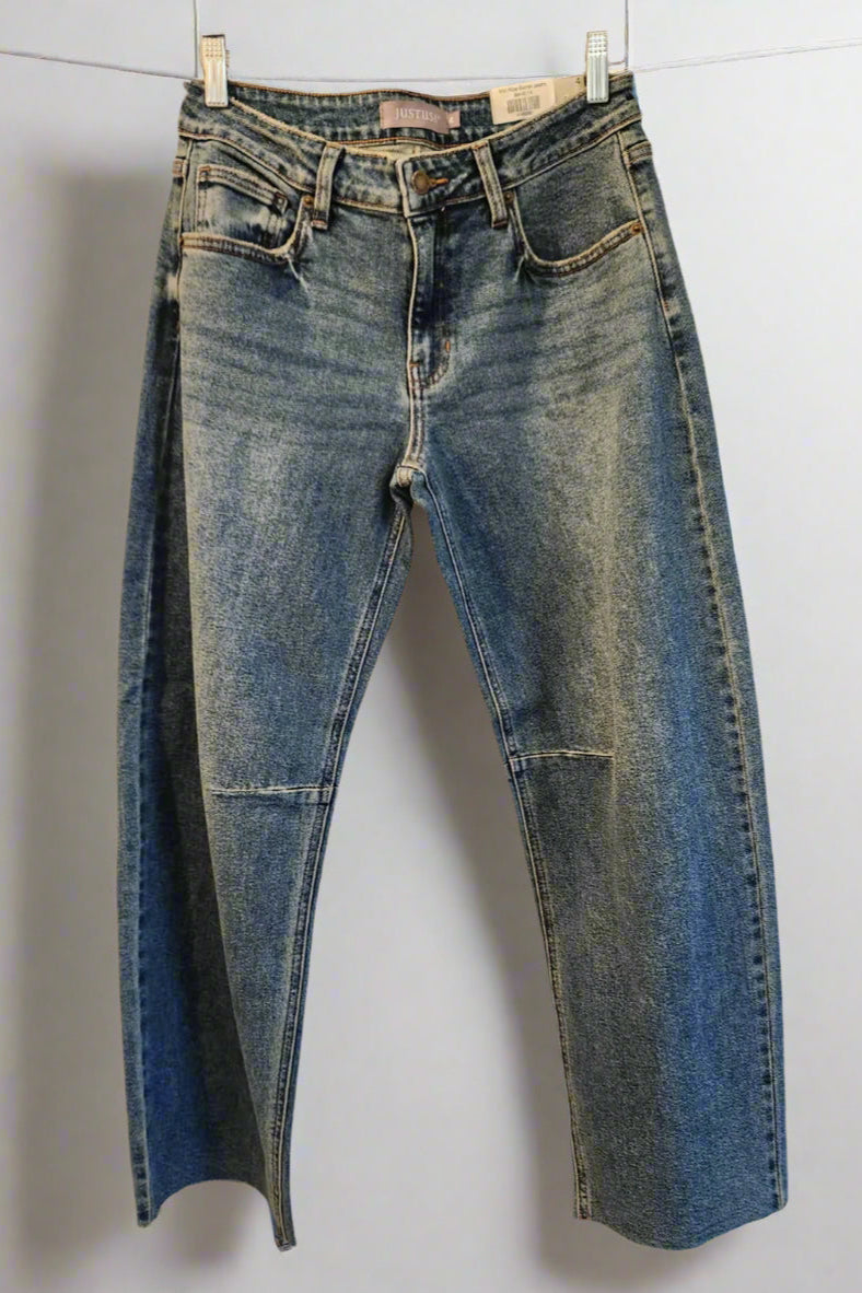 Pair of blue jeans hanging on a rack against a white background