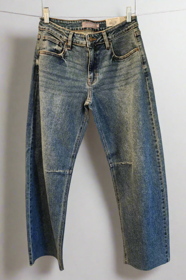 Pair of blue jeans hanging on a rack against a white background