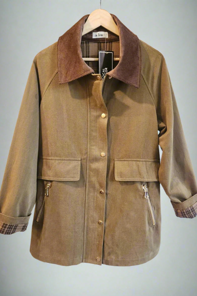 Brown jacket with plaid cuffs and collar on a hanger against a white background