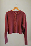 Maroon cardigan on a hanger against a plain background