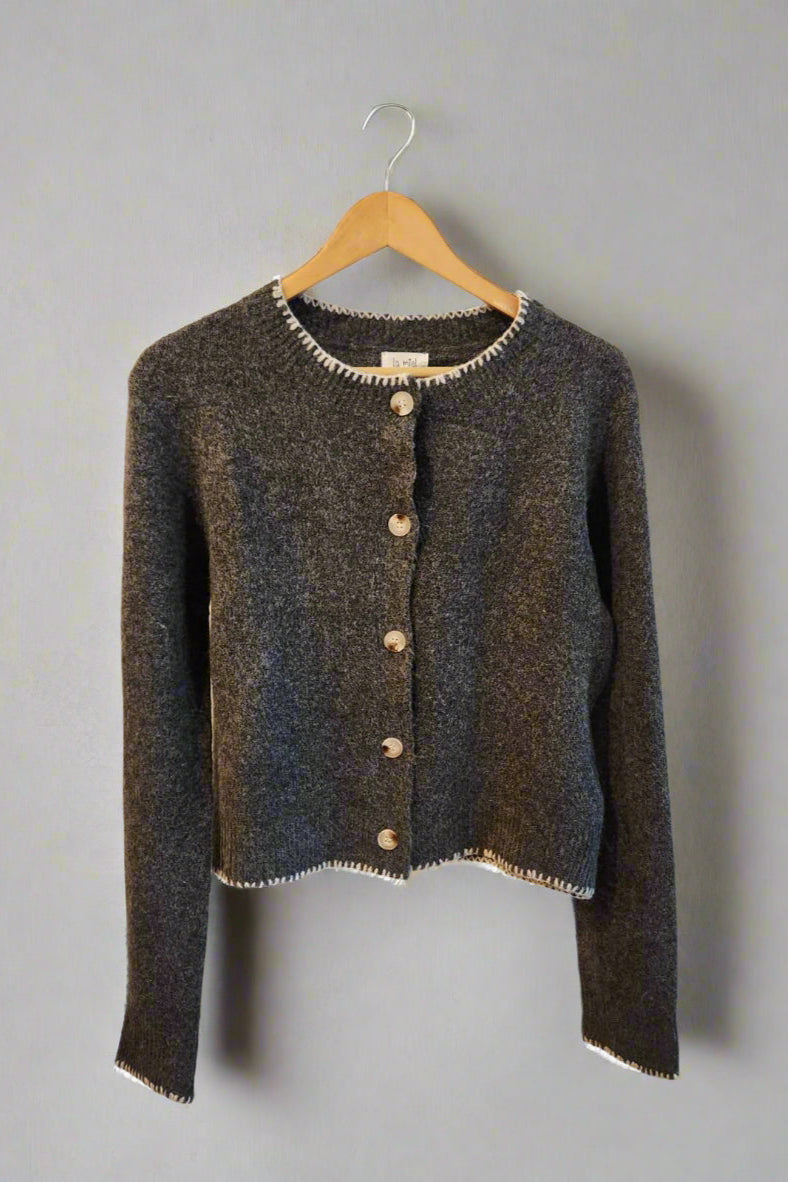 Dark gray textured cardigan with white trim on a hanger against a light background