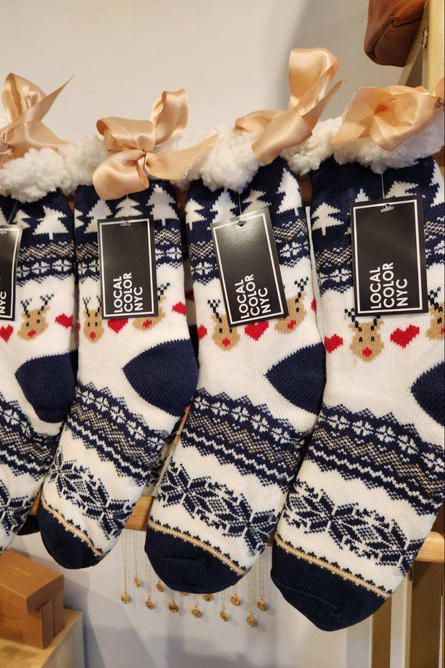 Set of patterned socks with ribbons and tags on a wooden rack.
