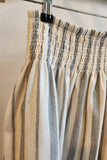 Striped skirt with a smocked waistband on a hanger against a neutral background