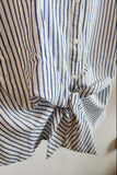 Close-up of a striped shirt with a knot on a neutral background