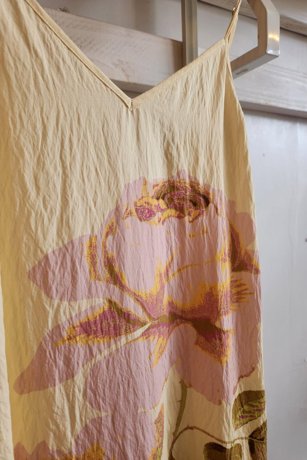Floral-patterned dress hanging on a rack against a white wall.
