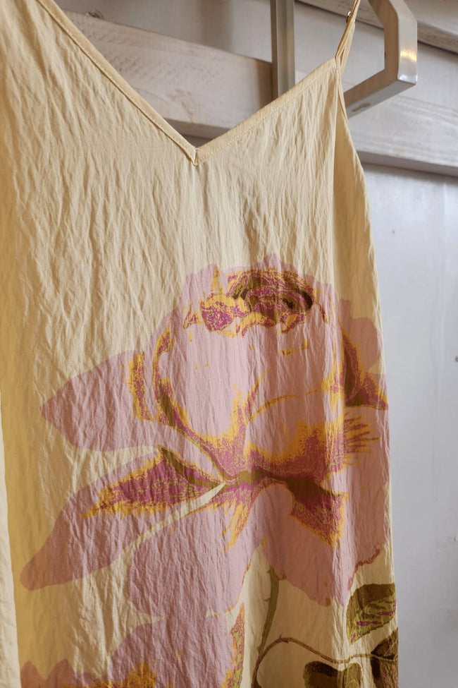 Floral-patterned dress hanging on a rack against a white wall.