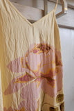 Floral-patterned dress hanging on a rack against a white wall.