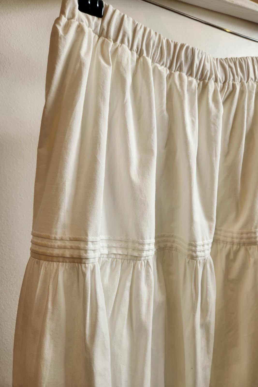 white skirt with a wooden hanger and clips on a neutral background