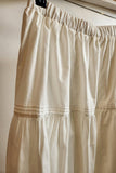 white skirt with a wooden hanger and clips on a neutral background