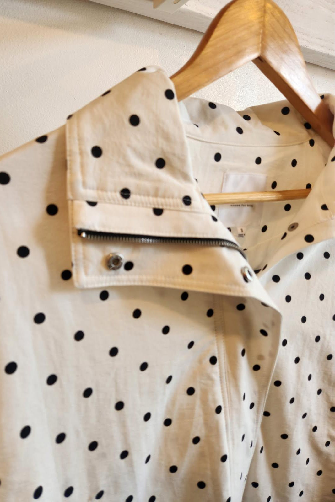 White jacket with black polka dots on a wooden hanger