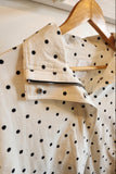 White jacket with black polka dots on a wooden hanger
