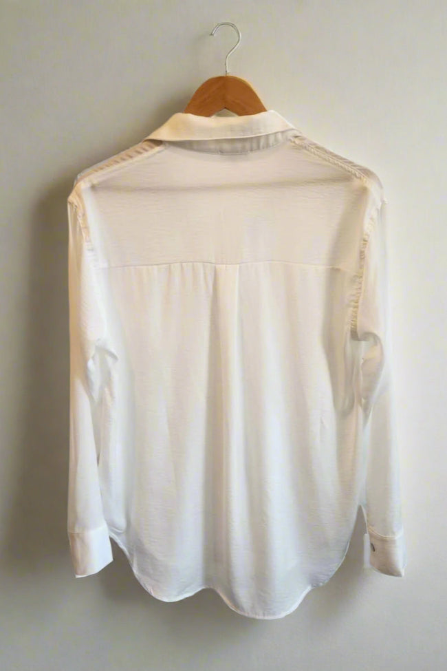 White blouse on a hanger against a plain background