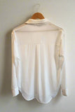 White blouse on a hanger against a plain background