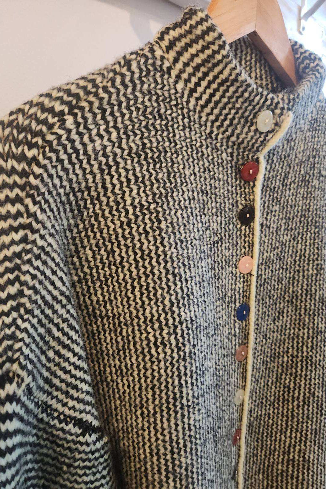 Textured sweater with button details against a neutral background