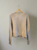 Beige sweater on a hanger against a plain background