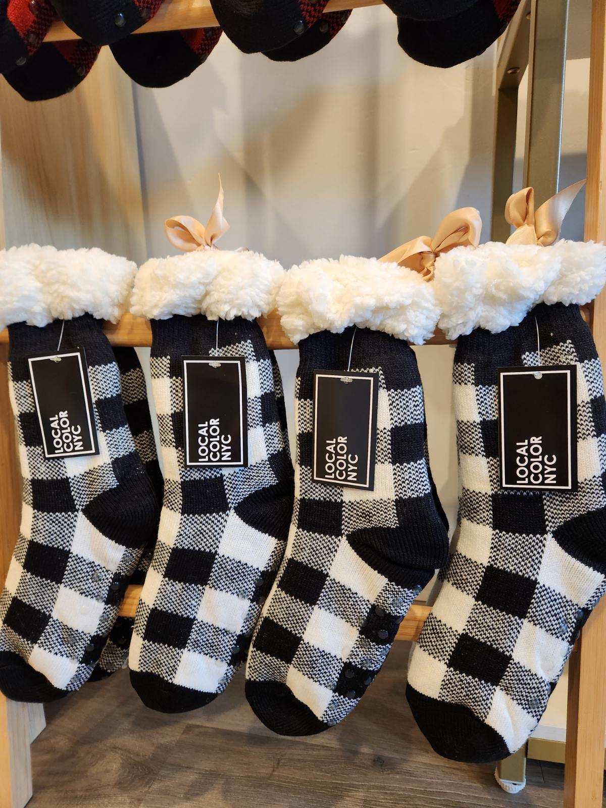 Black and white checkered socks with fluffy tops on a rack, featuring 'Local Color NYC' labels.