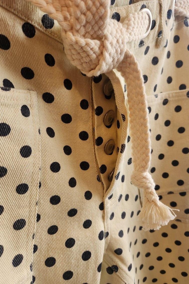 Close-up of a beige outfit with black polka dots and a knitted bow detail.