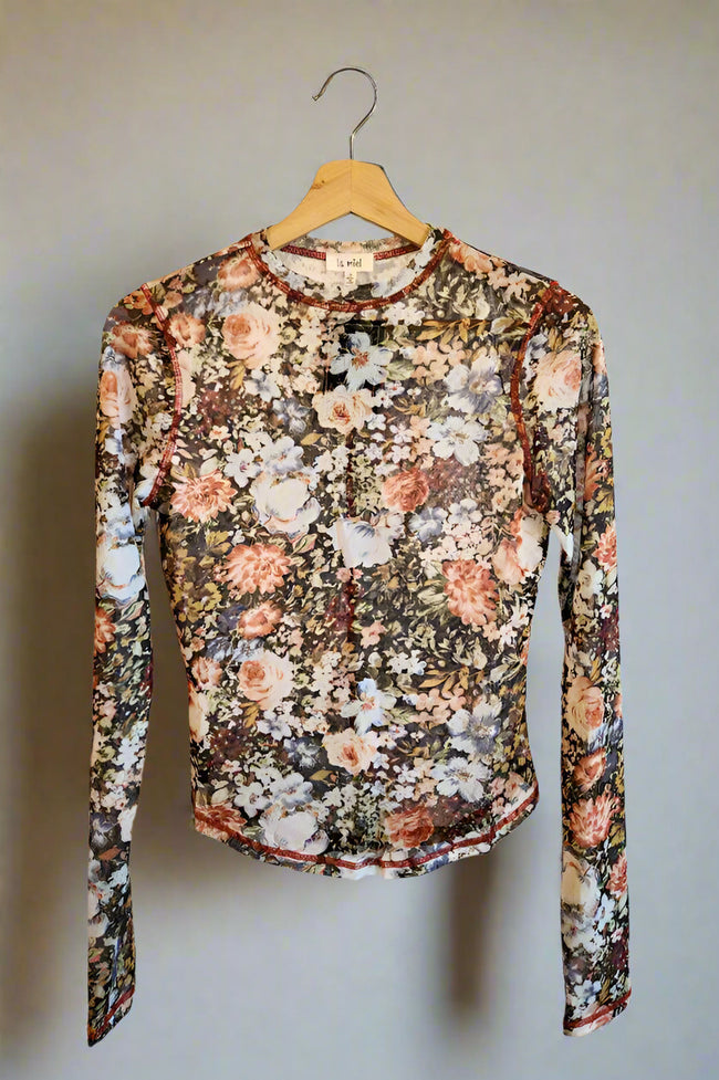 Floral patterned long-sleeve shirt on a hanger against a white wall