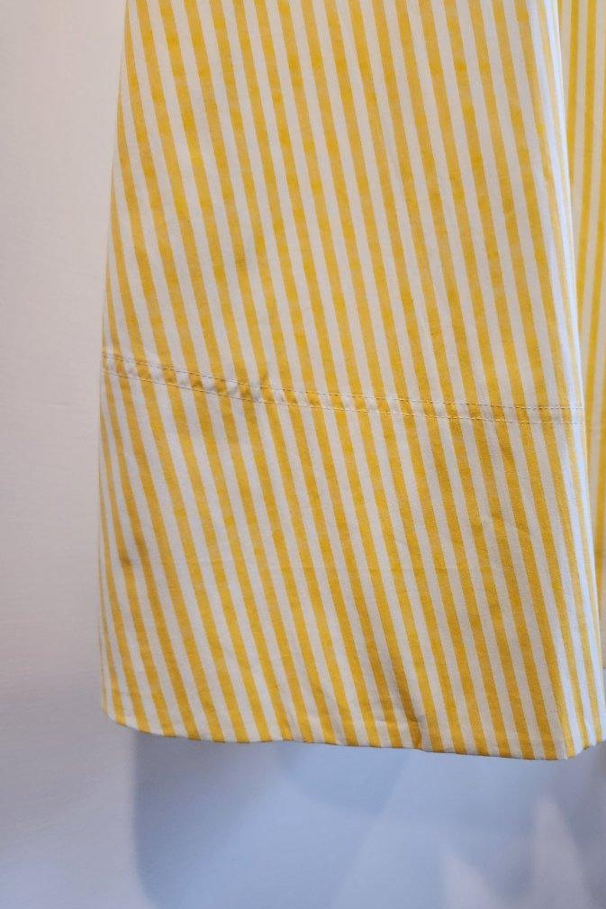 Yellow and white striped dress on a mannequin against a plain background