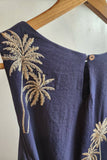 Navy blue dress with tan palm tree embroidery on a wooden hanger.
