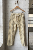 Polka dot pants hanging on a wooden hanger against a white brick wall.