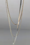 Three layered gold-tone and silver chain necklaces displayed on a neutral gray background.