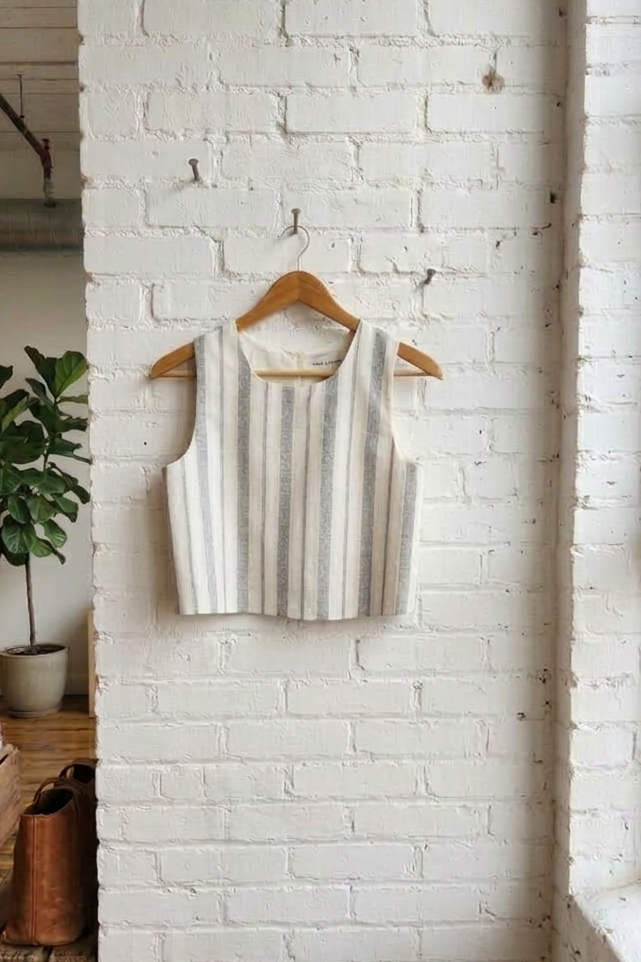 Striped shirt on a wooden hanger against a white brick wall.