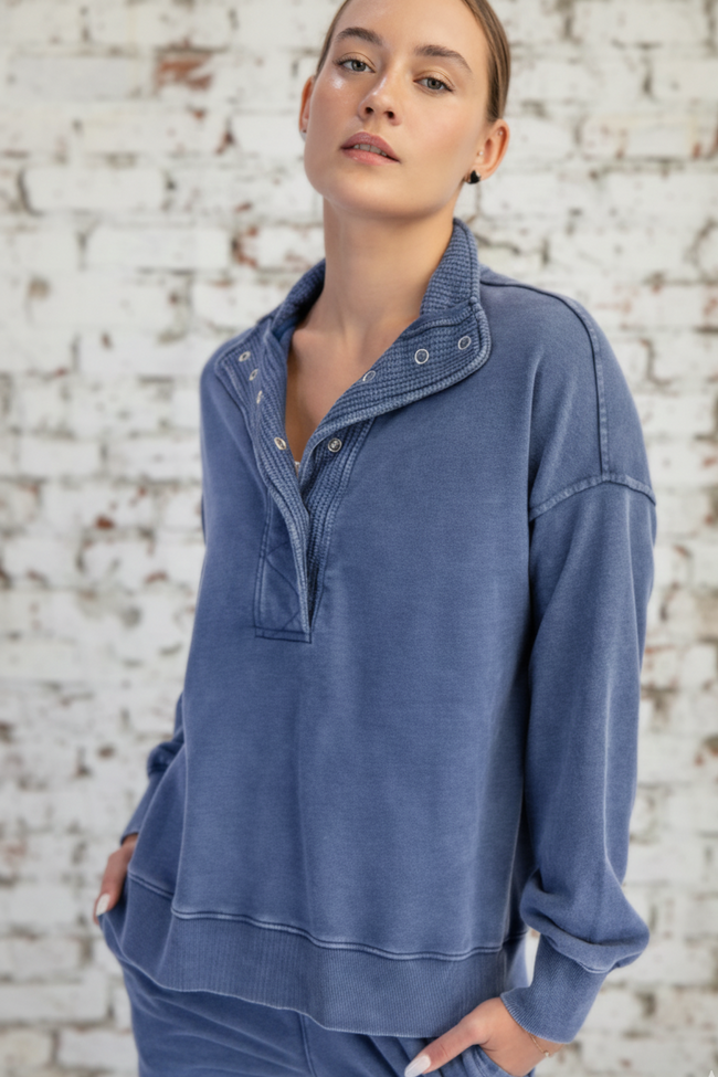 Woman wearing a blue pullover with a brick wall background