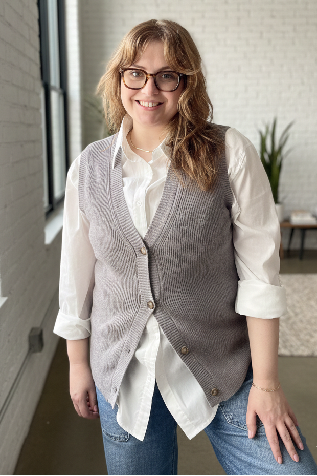 Woman wearing a gray vest over a white shirt in an office setting