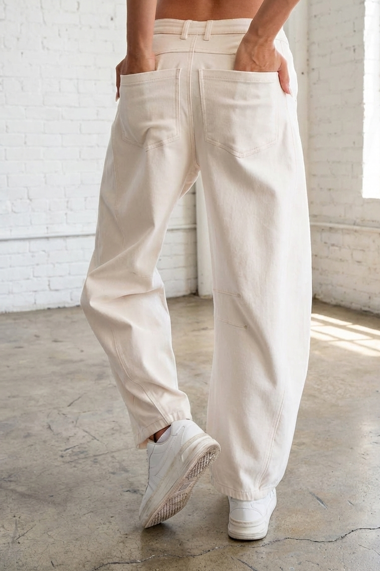Person wearing beige pants and white sneakers in a room with white brick walls.