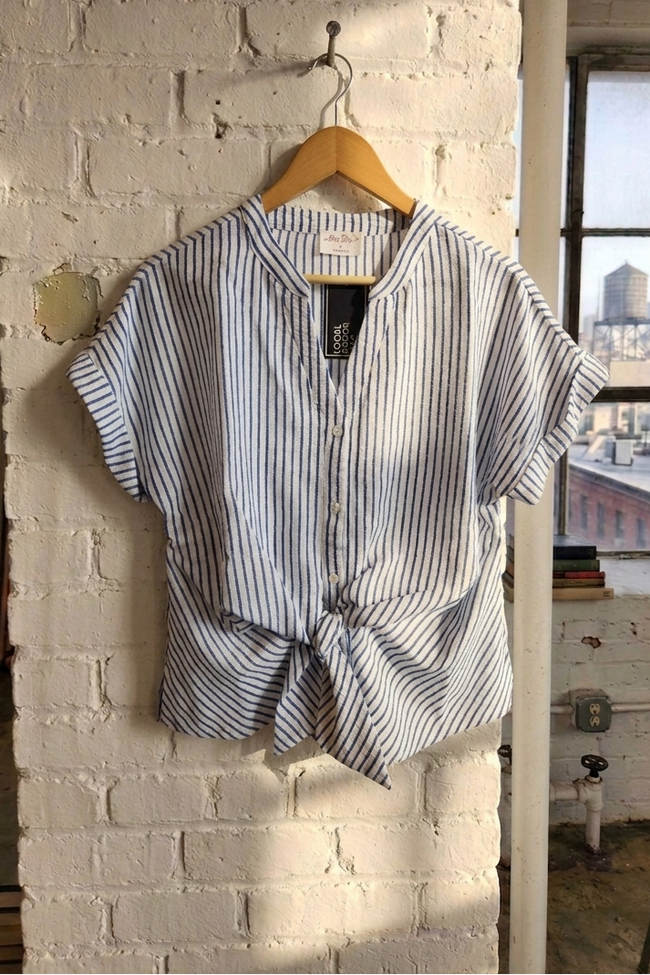 Striped shirt on a hanger against a brick wall with a cityscape view.