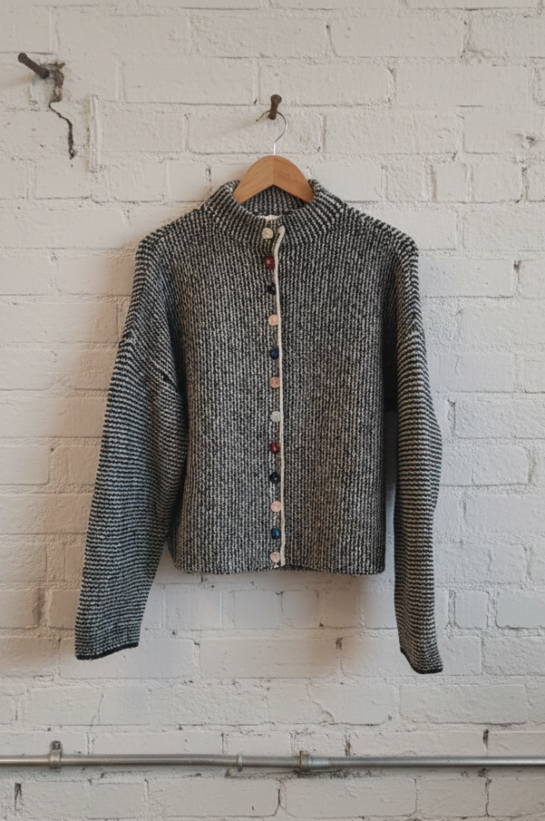 Textured sweater hanging on a hook against a white brick wall