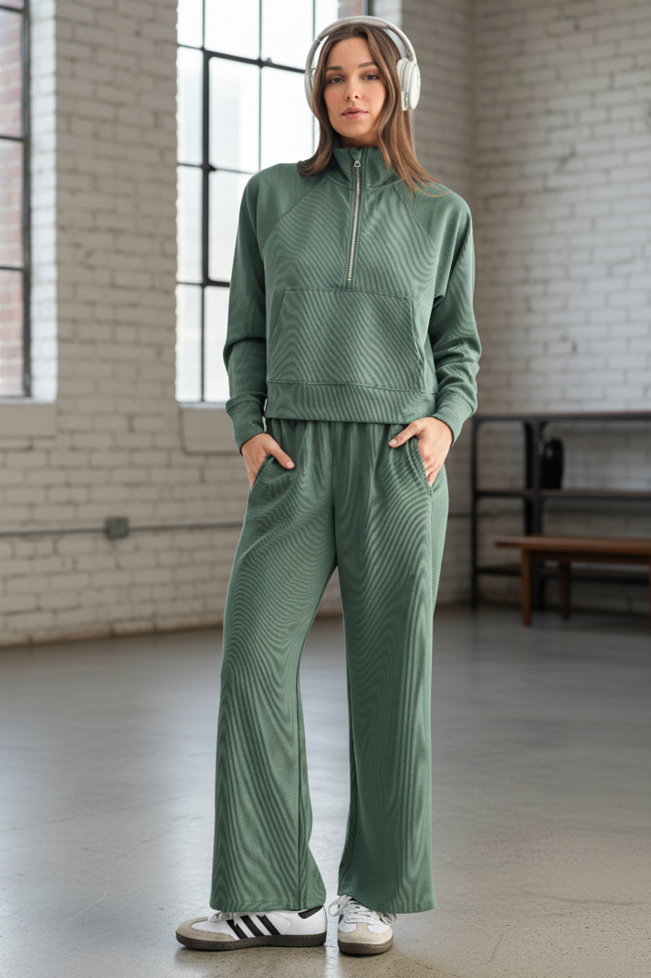 Person wearing a green tracksuit with white headphones in an indoor setting.