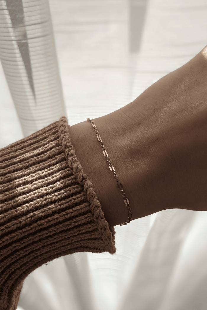 A close-up image of a person's wrist wearing a gold-filled chain bracelet with a dapped design and a lobster clasp.